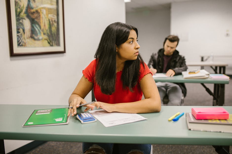 Students taking a test in a classroom, with one woman looking sideways. Education theme