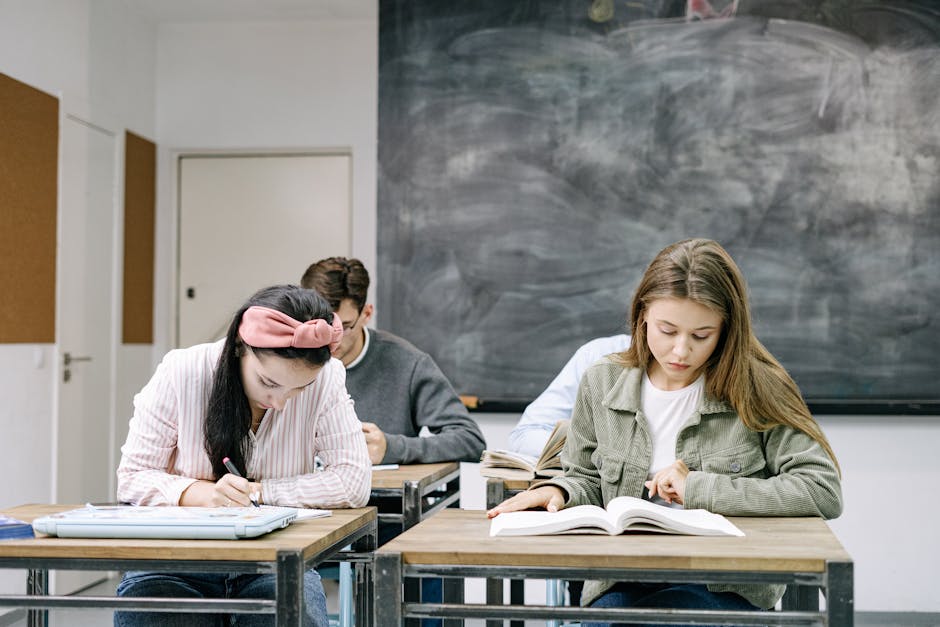 Young students studying in a classroom, focused on reading and writing assignments